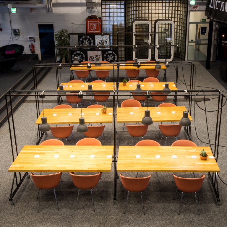 A co-working space with four rows of yellow wooden tables with chairs.