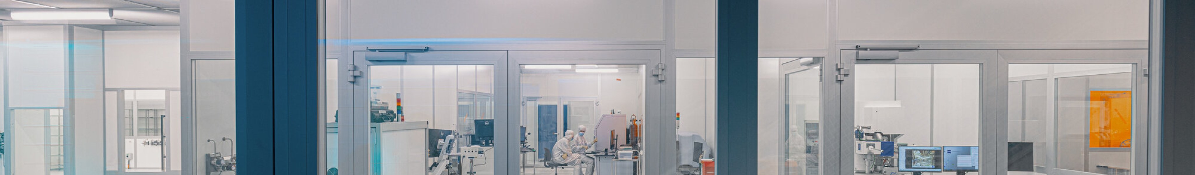 Quantum tech laboratory behind two glass doors with two people inside wearing white lab overalls