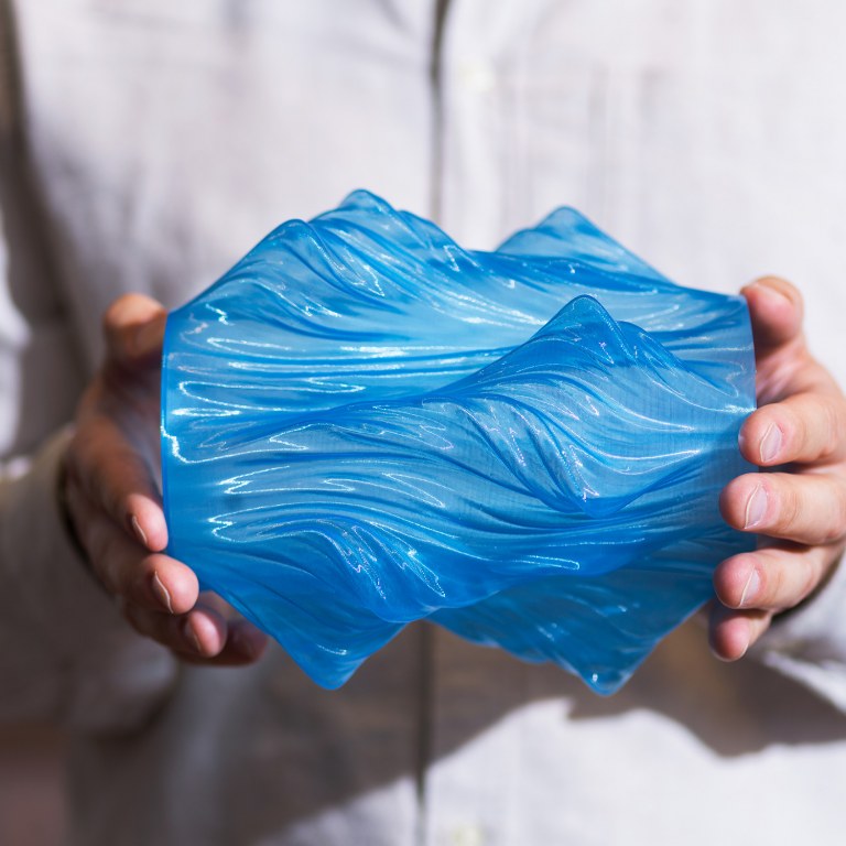 A closeup of hands holding blue 3D printmaterial.
