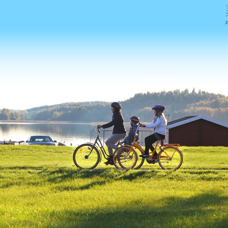 A woman and two children are cycling by the lake in Vihti.