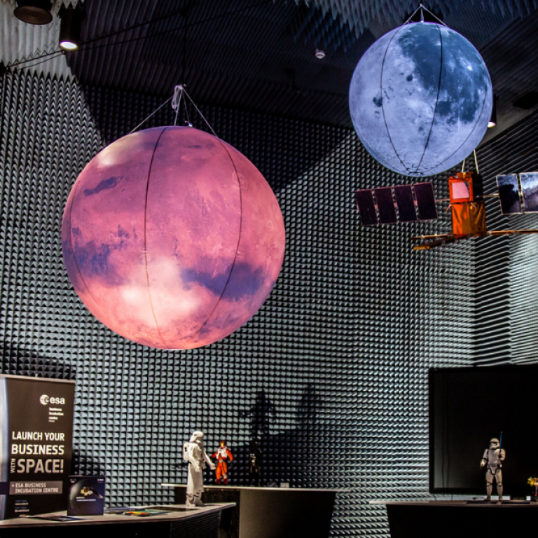 A darkly lit room with blue and pink planets hanging from ceiling and stormtrooper action figures standing on tables