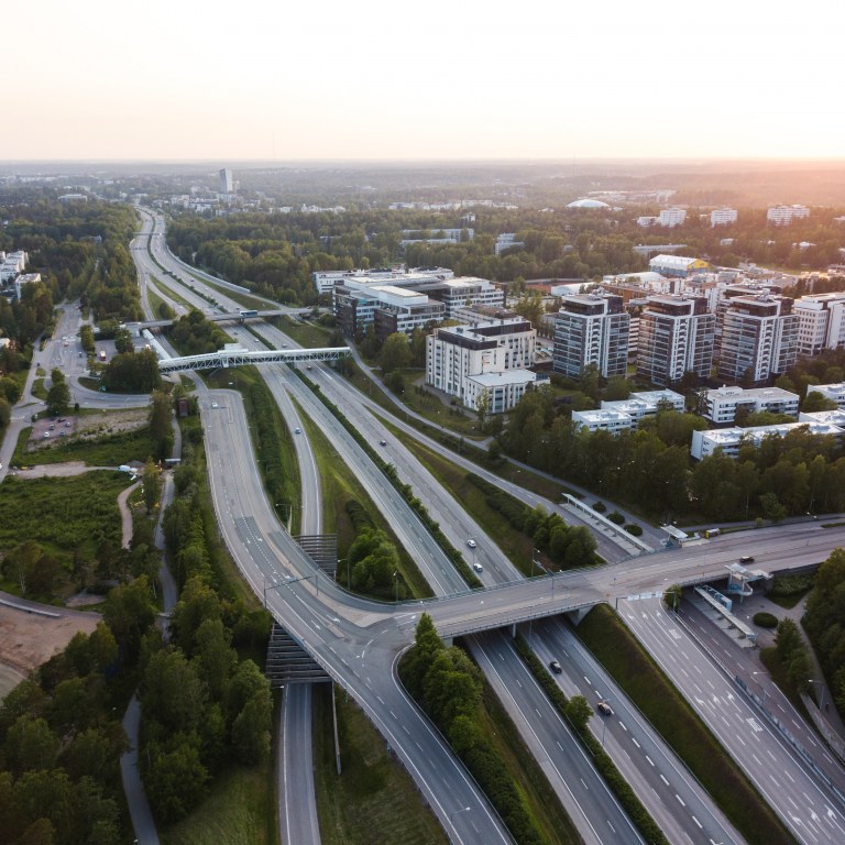 Picture of a motorway going through a city scenery of buildings and trees.