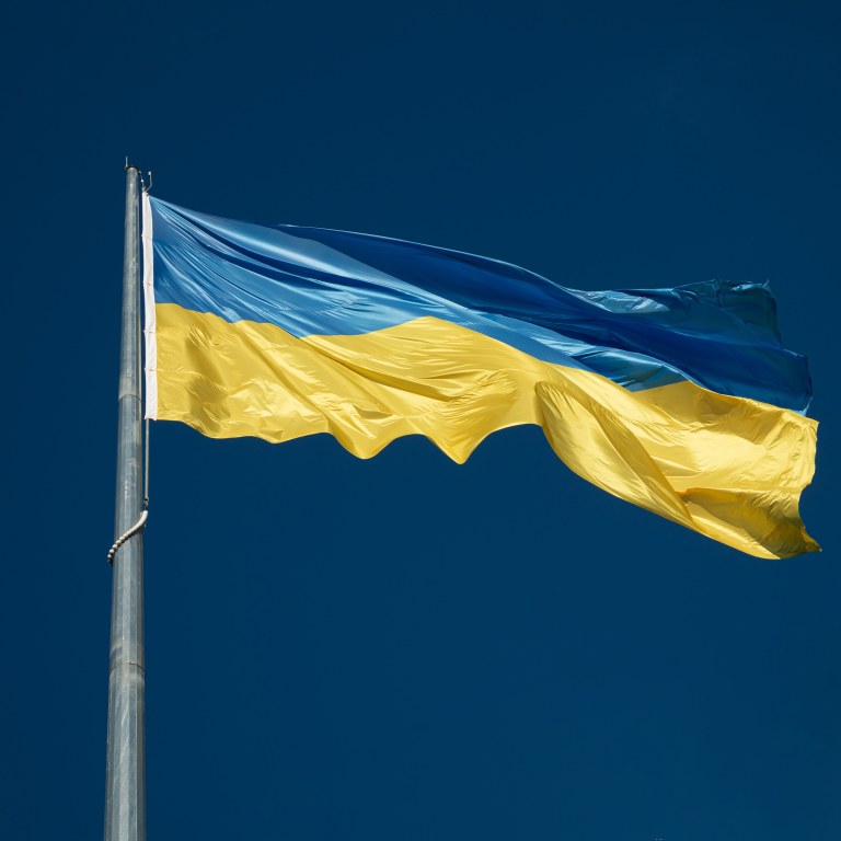 The flag of Ukraine flowing in a breeze on a clear blue sky.
