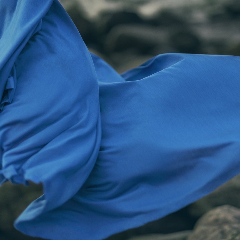 Blue fabric flying in the wind above rocks