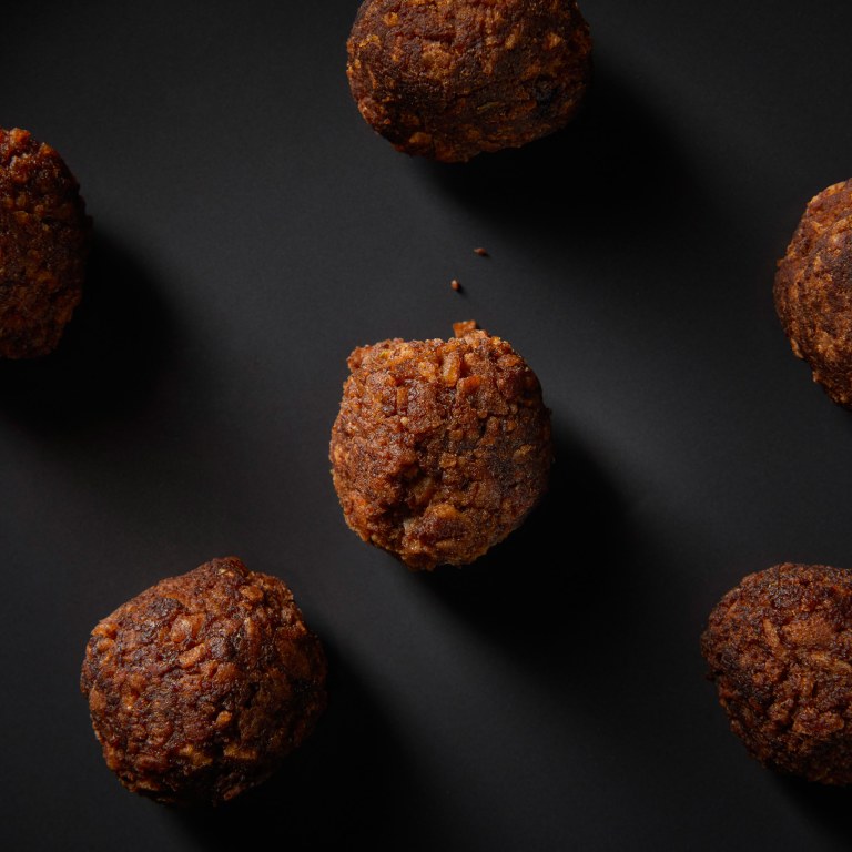 Six meat ball looking food products made of sustainable mycoprotein on a dark grey surface.
