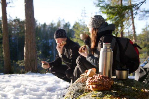 Two people drinking coffee outside in the forest