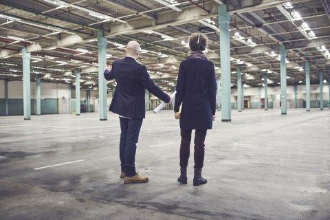 Two people standing inside a vast and empty hall.