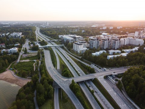 Picture of a motorway going through a city scenery of buildings and trees.