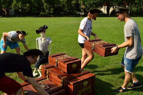 Four people solving a treasure chest puzzle in an escape game outdoors.