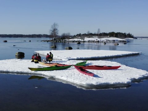 On a winter kayaking trip, a group taking a break on an ice raft