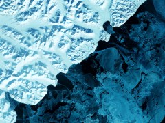 Cold blue satellite image of a glacier melting into water.