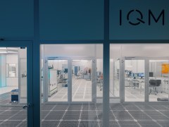 Quantum tech laboratory behind two glass doors with two people inside wearing white lab overalls